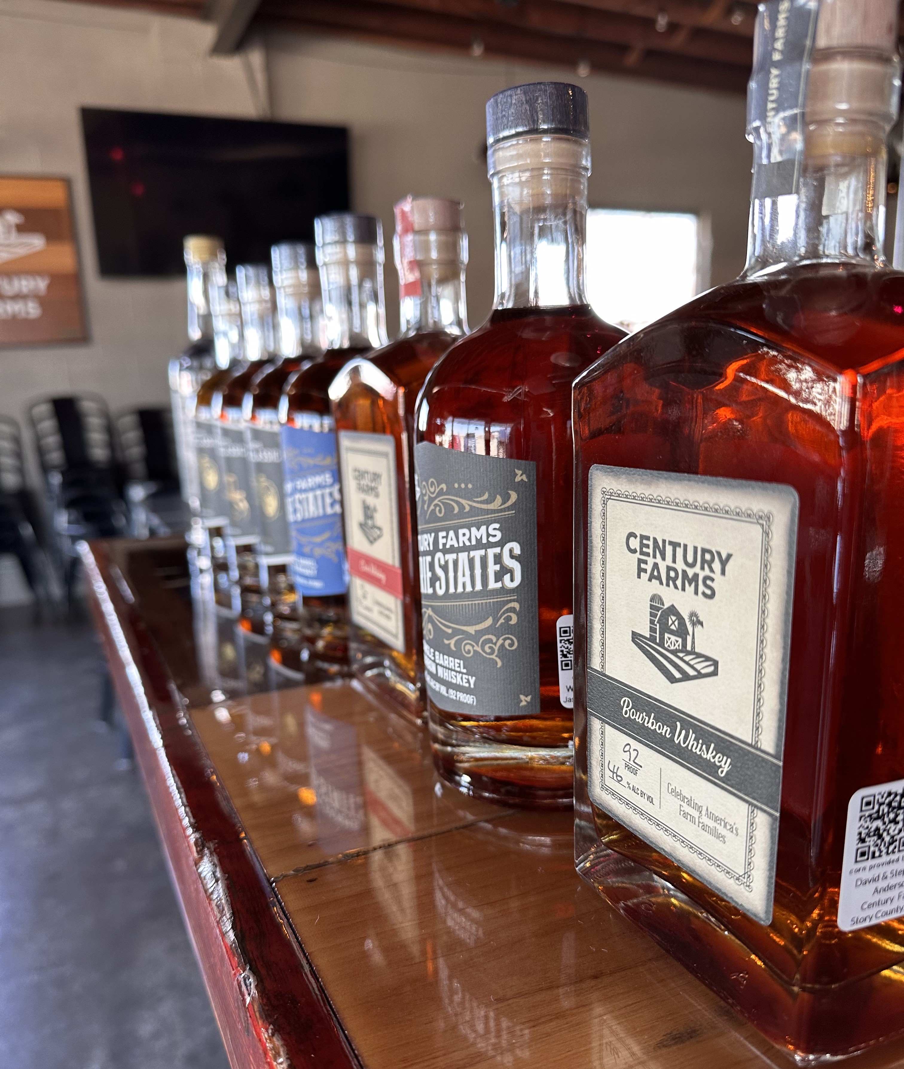 A row of whiskey bottles sit on top of a bar.