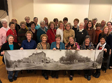 A group of women gather to hold a large banner of the history building they are saving